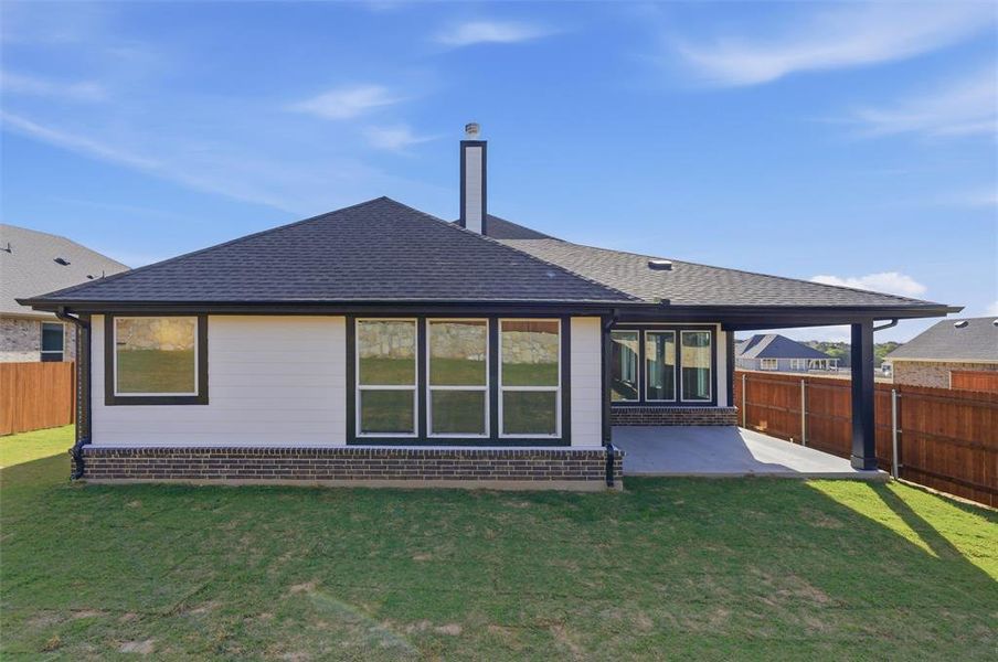 Back of property featuring a fenced backyard, roof with shingles, a patio, and a chimney