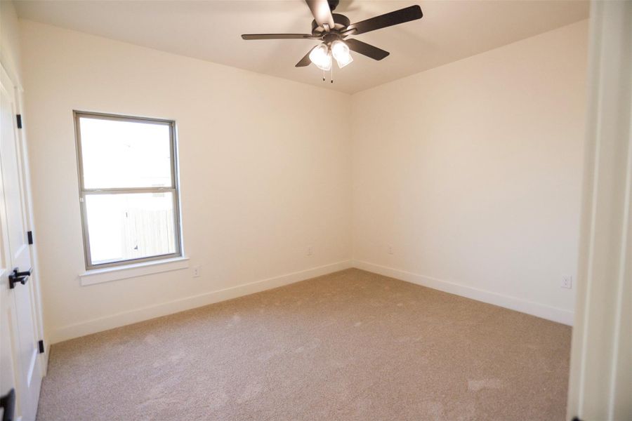 Carpeted spare room with baseboards and a ceiling fan