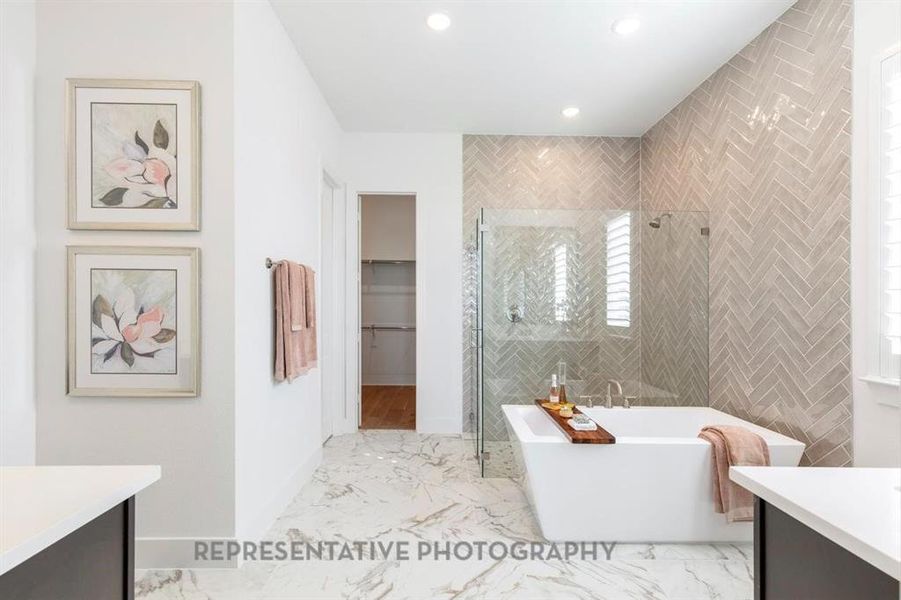 Bathroom featuring vanity, a spacious closet, a stall shower, a soaking tub, and light marble finish flooring