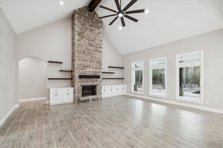 Built in closed storage cabinets with quartz top.  Floating shelves above the cabinets.  Floor to ceiling brick fireplace with dark mantle.   20 ft. Vaulted dark beam ceiling with large lighted fan. Arched opening leads to the hallway with secondary bedrooms and baths.