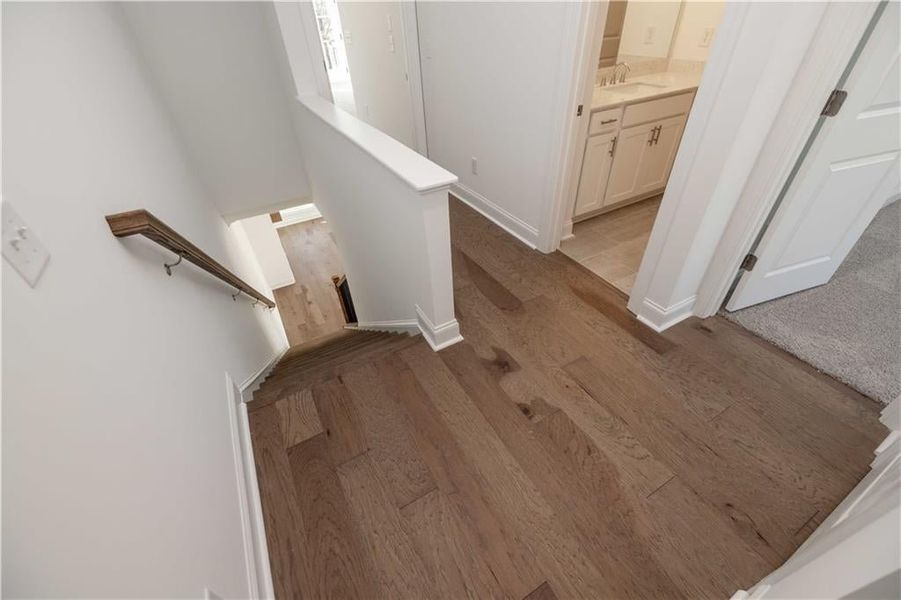 Hard Surface flooring in the hallway on the upper level leads to the Primary Suite and Secondary Bedrooms.