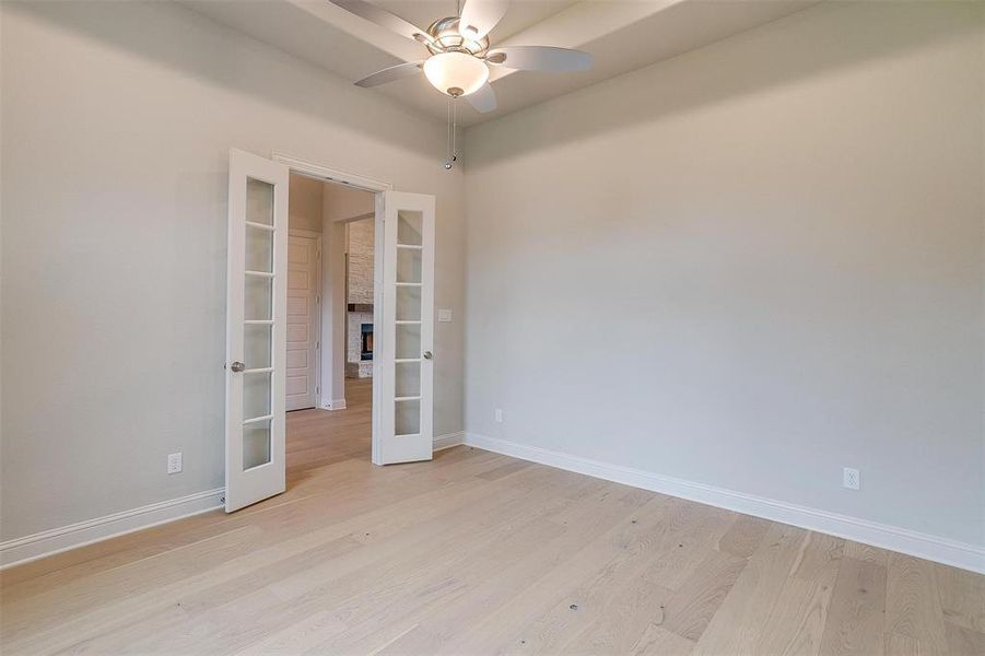 Empty room with french doors, light wood-type flooring, and ceiling fan