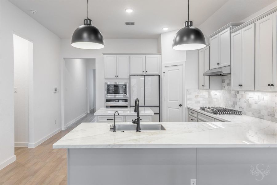 The gourmet kitchen shines with sleek porcelain countertops, a spacious breakfast bar, and modern pendant lighting that elevates the space. Abundant cabinetry and stainless steel appliances complete this light-filled culinary setting. The gourmet kitchen shines with sleek porcelain countertops, a spacious breakfast bar, and modern pendant lighting that elevates the space. Abundant cabinetry and stainless steel appliances complete this light-filled culinary setting.