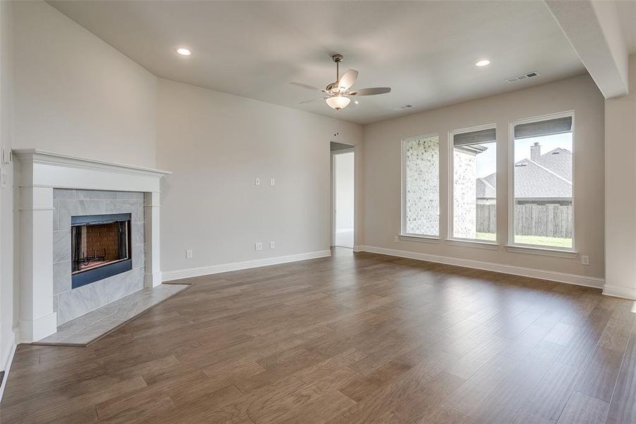 Unfurnished living room featuring ceiling fan, a fireplace, and dark hardwood / wood-style floors