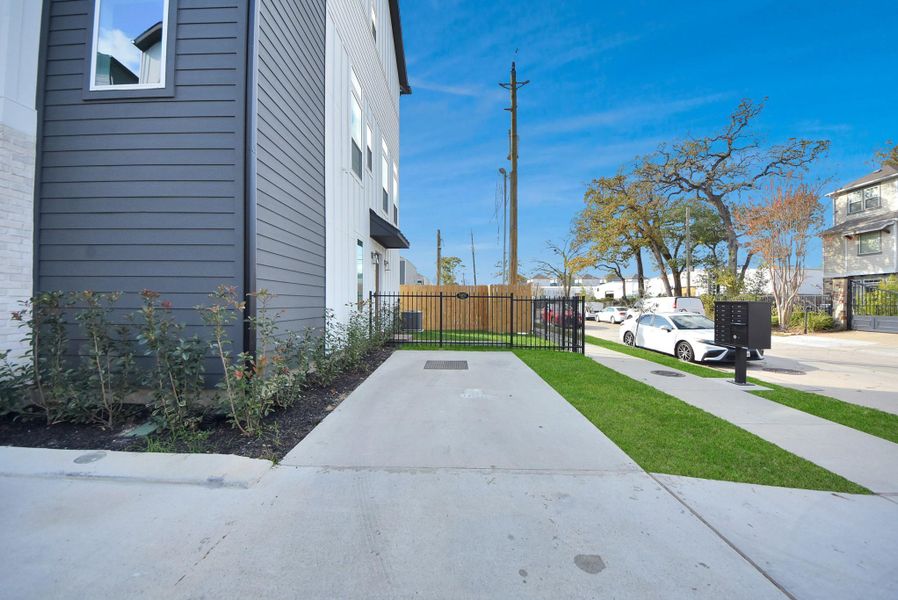 Approach the home from a clean, modern exterior featuring gray siding, a gated entrance, and manicured landscaping. Street parking is available in this quiet, friendly neighborhood.