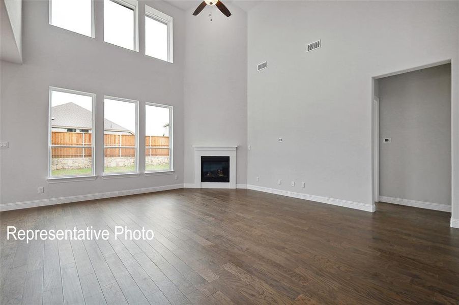 Unfurnished living room featuring ceiling fan, hardwood / wood-style floors, and a high ceiling