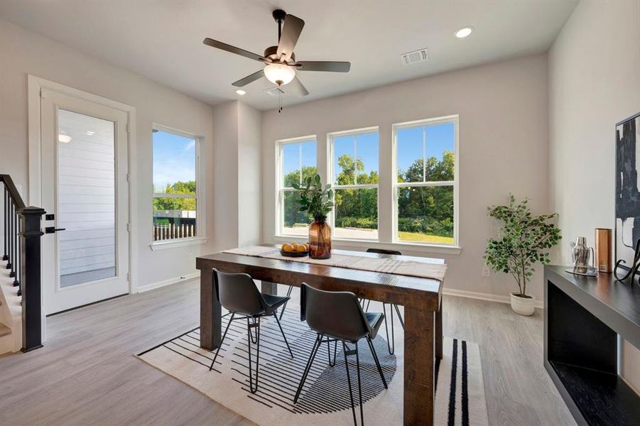 Dining area featuring three large windows, wood-finish flooring, a ceiling fan with integrated lighting, and recessed lighting