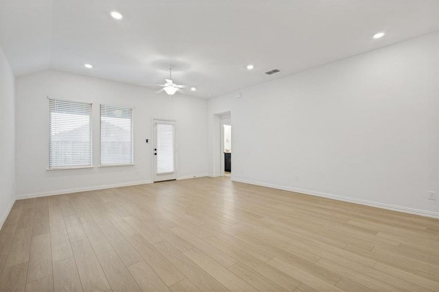 Spacious room featuring vaulted ceilings, recessed lighting, wood-finish flooring, and a ceiling fan