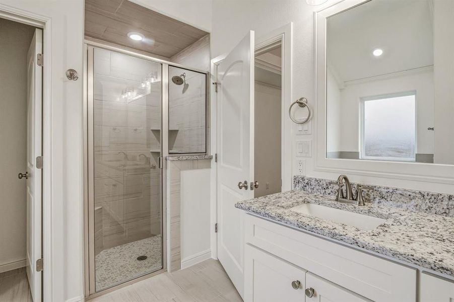 The bathroom features a vanity with a granite countertop, a built-in sink, and a framed mirror