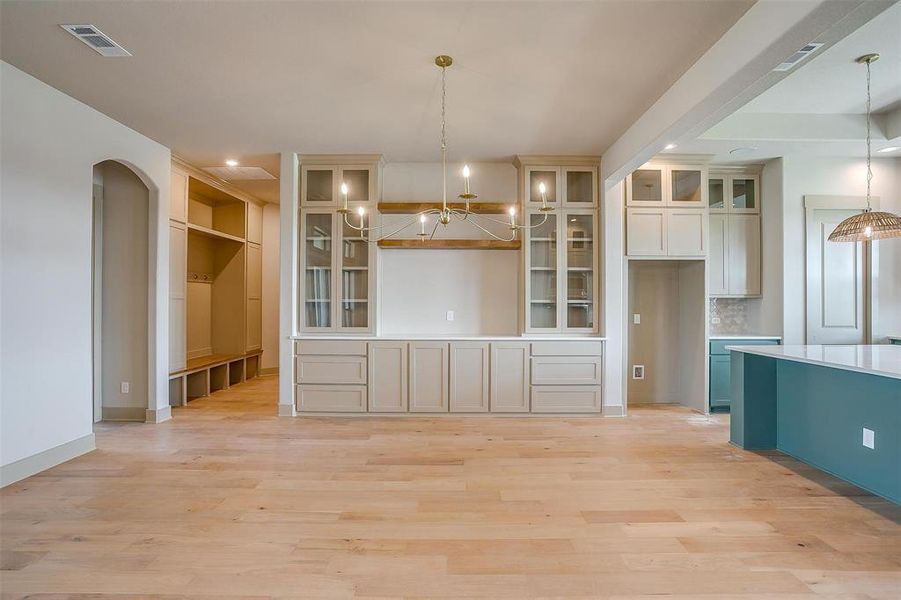 Unfurnished dining area with recessed lighting, an inviting chandelier, light wood-type flooring, visible vents, and arched walkways