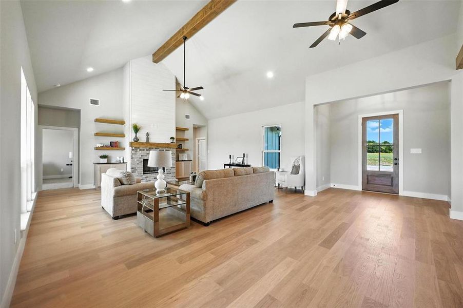 Living area with ceiling fan, light wood-type flooring, a brick fireplace, and recessed lighting