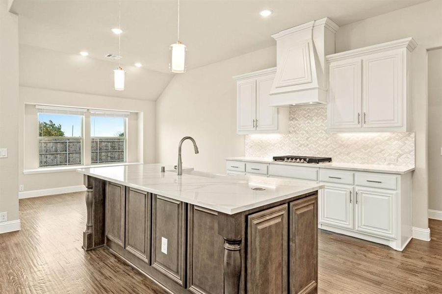 Kitchen with white cabinetry, decorative backsplash, light stone counters, an island with sink, and recessed lighting