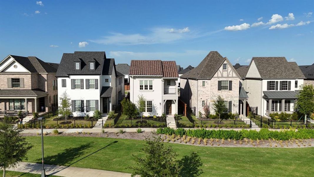 White two-story residence featuring black shutters, a dark shingled roof with dormer windows, and a paved walkway leading to the front entry