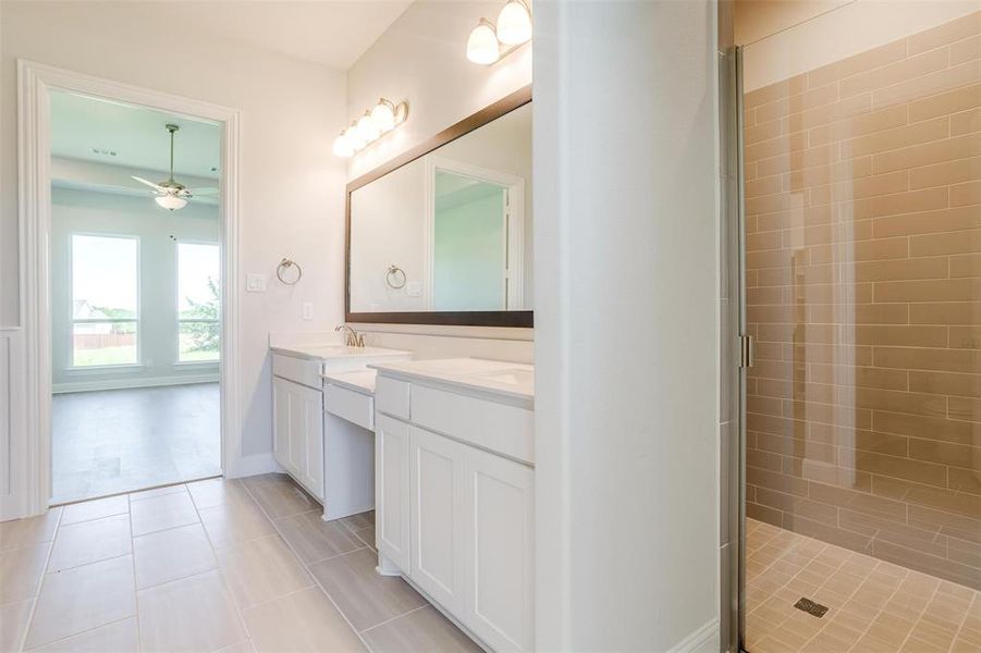 Bathroom with ceiling fan, tile patterned floors, walk in shower, and dual vanity