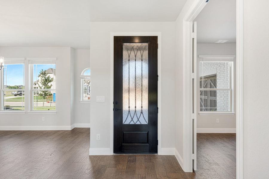 Home entryway with dark wood front door featuring decorative glass panel and hardwood floors Home entryway with dark wood front door featuring decorative glass panel and hardwood floors