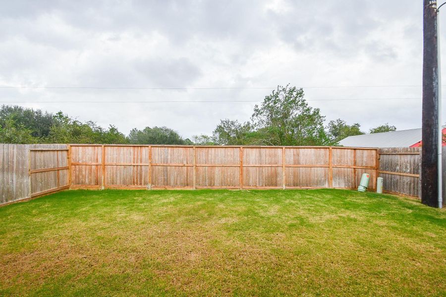 A spacious fenced backyard with plenty of room for entertaining, gardening, or play.