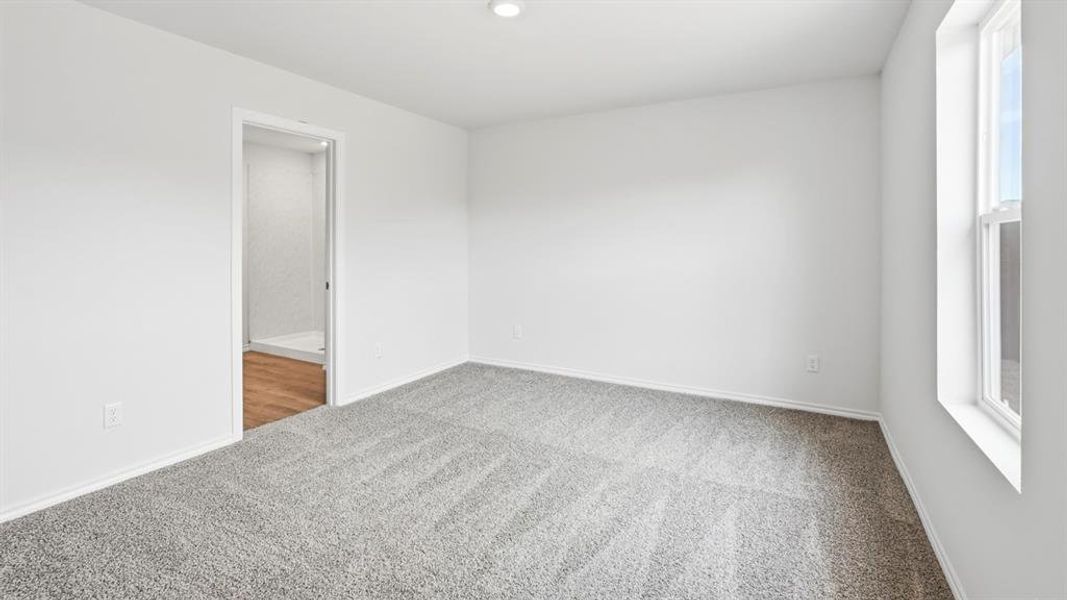 Room featuring light grey carpeting, white walls, and a window providing natural light