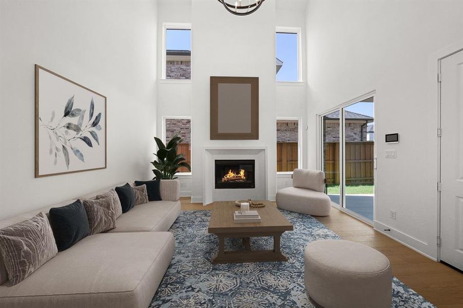 Living area featuring wood finished floors, a glass covered fireplace, and a towering ceiling
