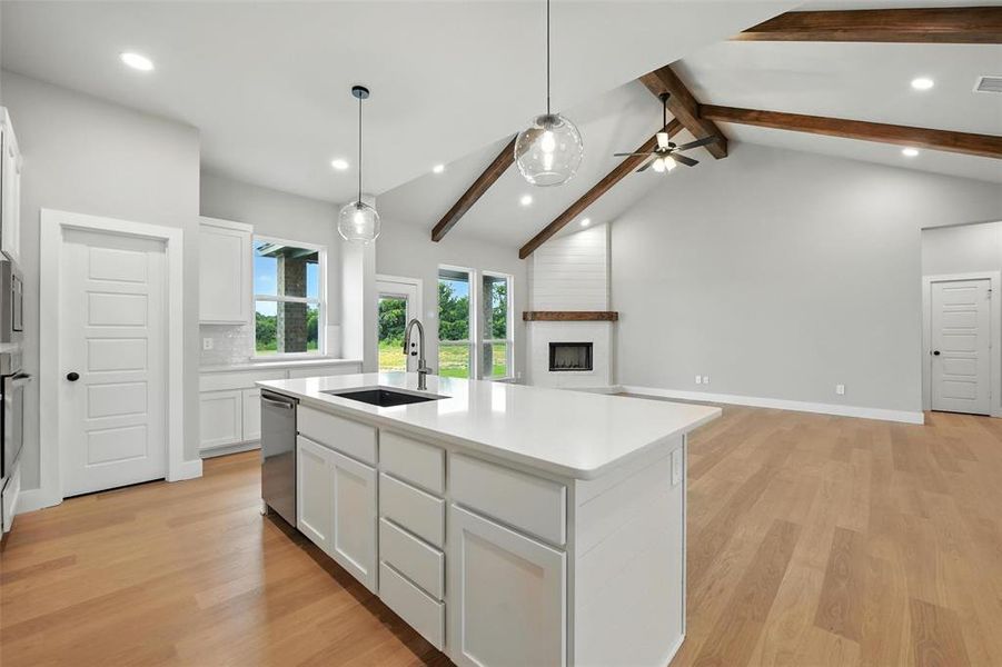 Kitchen with a fireplace, appliances with stainless steel finishes, open floor plan, a kitchen island with sink, and white cabinetry Kitchen with a fireplace, appliances with stainless steel finishes, open floor plan, a kitchen island with sink, and white cabinetry
