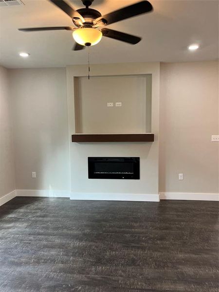 Unfurnished living room featuring dark wood-type flooring and ceiling fan