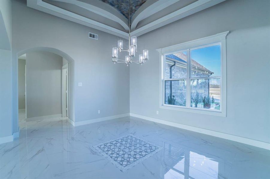 Unfurnished dining area featuring light marble finish flooring, a chandelier, and arched walkways
