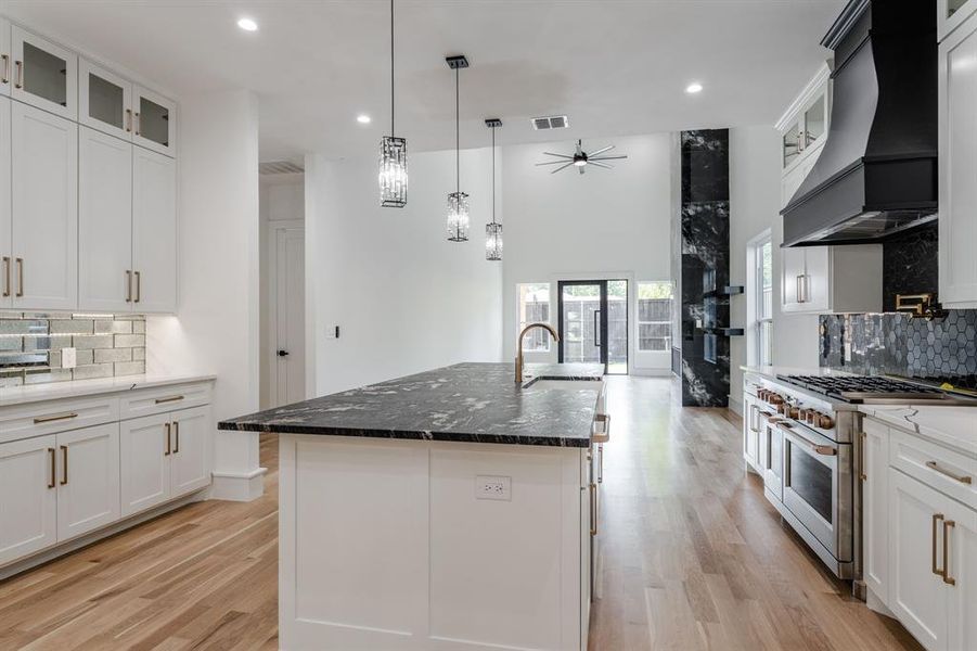 Kitchen featuring decorative backsplash, glass insert cabinets, white cabinetry, recessed lighting, and a towering ceiling Kitchen featuring decorative backsplash, glass insert cabinets, white cabinetry, recessed lighting, and a towering ceiling