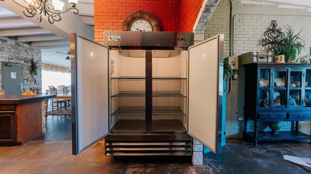 Basement featuring brick wall, a ceiling fan, and a chandelier