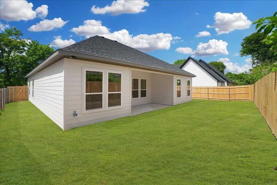 Expansive backyard featuring a lush lawn, privacy fencing, and a concrete patio Expansive backyard featuring a lush lawn, privacy fencing, and a concrete patio