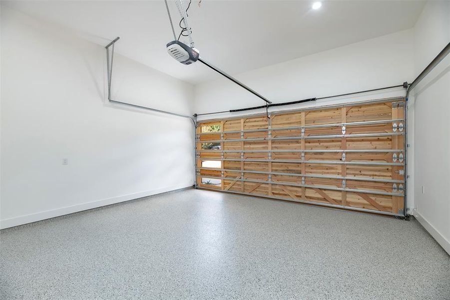 Garage featuring baseboards and a garage door opener Garage featuring baseboards and a garage door opener