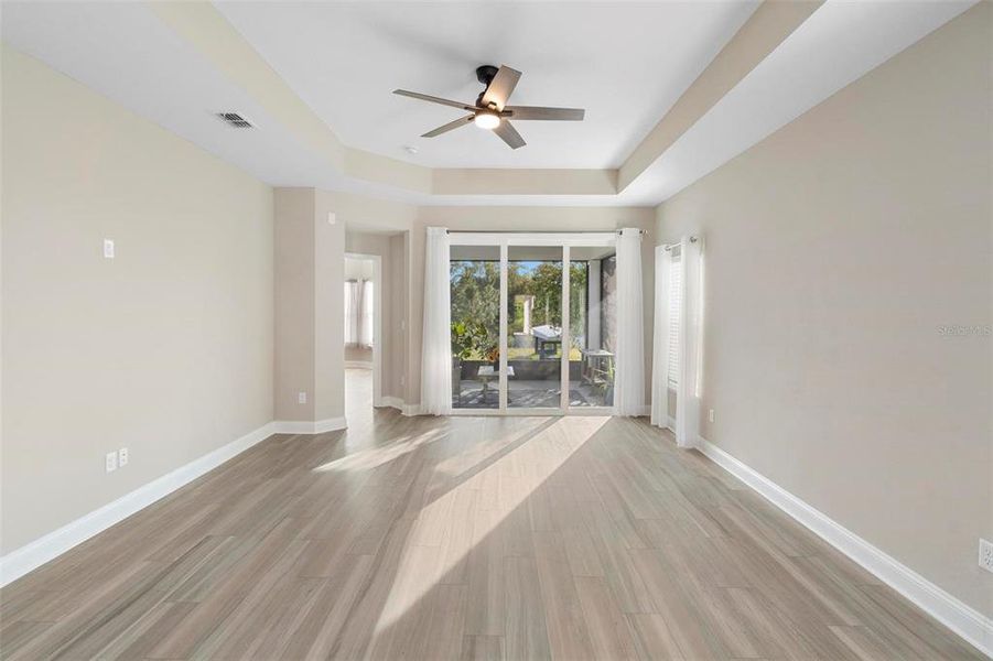 The tray ceiling, complemented by a stylish fan, enhances the luxurious feel of the space while allowing natural light to fill the room, creating the perfect ambiance for both relaxation and entertainment.