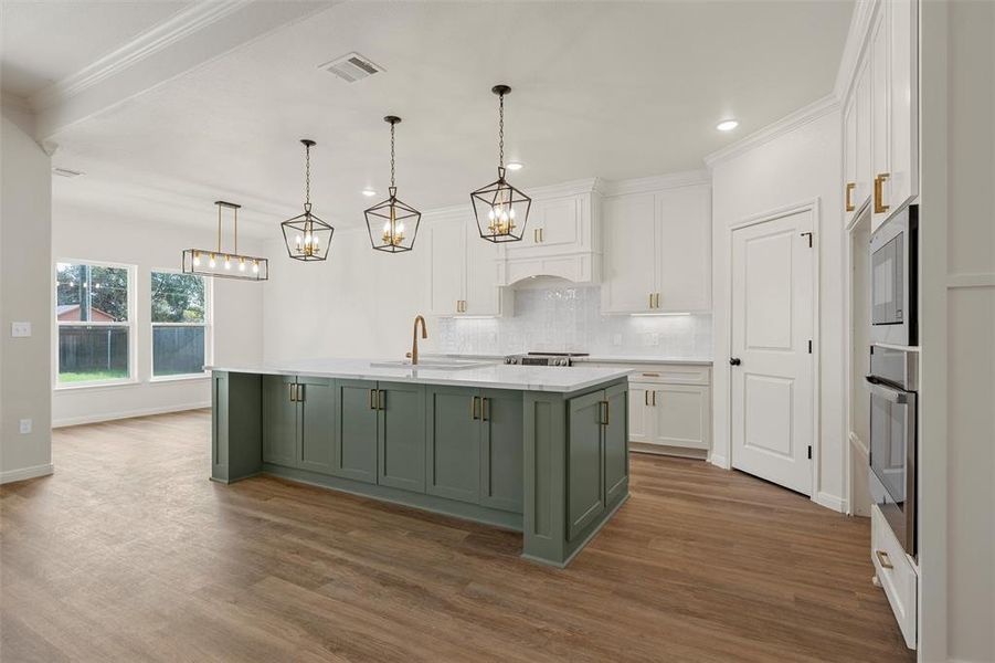 Kitchen with white cabinets, stainless steel appliances, light stone counters, decorative light fixtures, and ornamental molding Kitchen with white cabinets, stainless steel appliances, light stone counters, decorative light fixtures, and ornamental molding