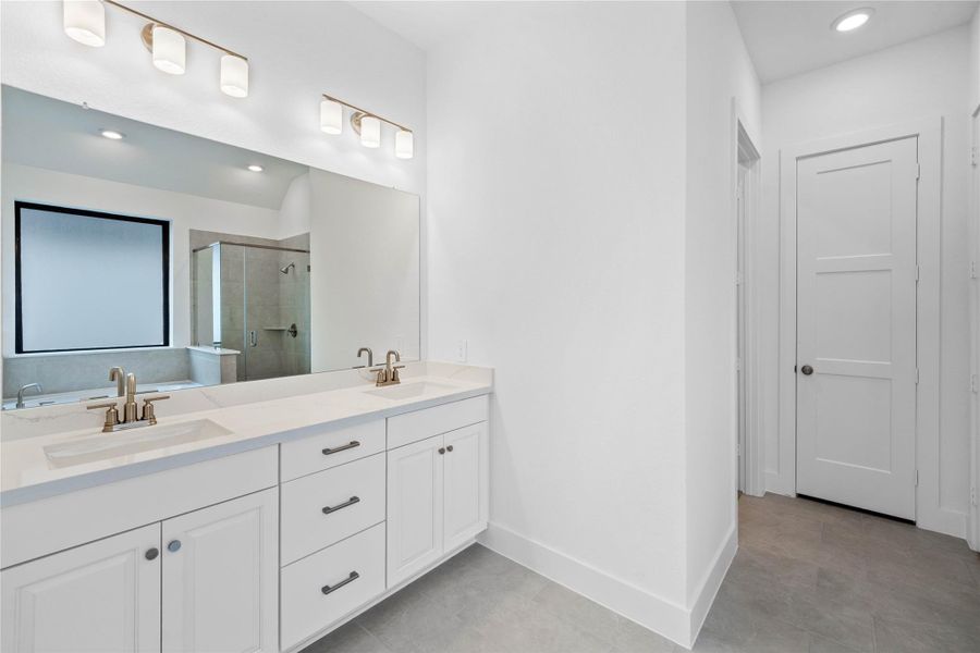 This stunningly updated primary bathroom is truly move-in ready! It features stained cabinetry with light countertops, dual vanities, a large mirror, high ceilings, custom paint, and sleek modern finishes throughout.