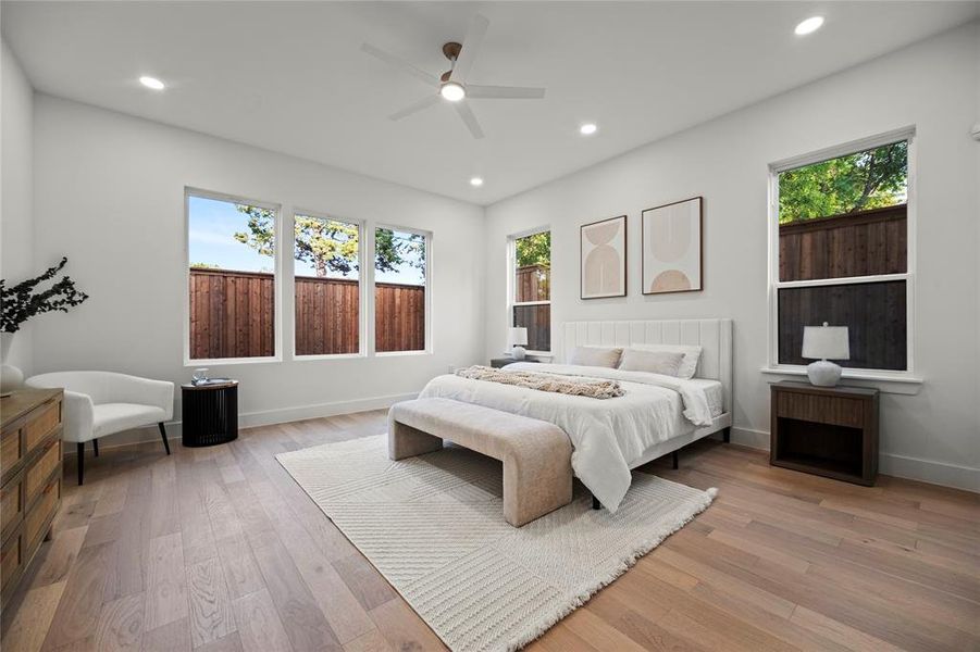 Bedroom with light hardwood / wood-style flooring, ceiling fan, and multiple windows