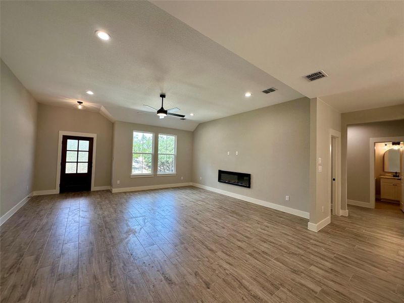 Unfurnished living room with a ceiling fan, wood finished floors, a glass covered fireplace, and recessed lighting Unfurnished living room with a ceiling fan, wood finished floors, a glass covered fireplace, and recessed lighting