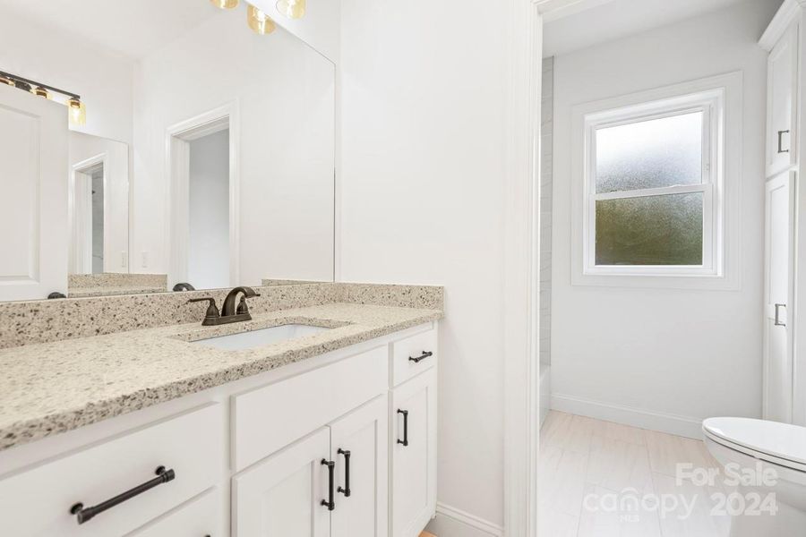 The second full bath on the upper level features a tile shower/tub combo and vanity with granite counter tops