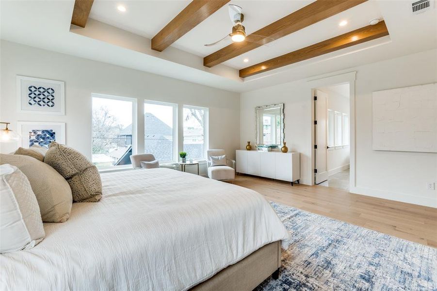 Bedroom featuring beamed ceiling, ensuite bathroom, ceiling fan, and light hardwood / wood-style flooring