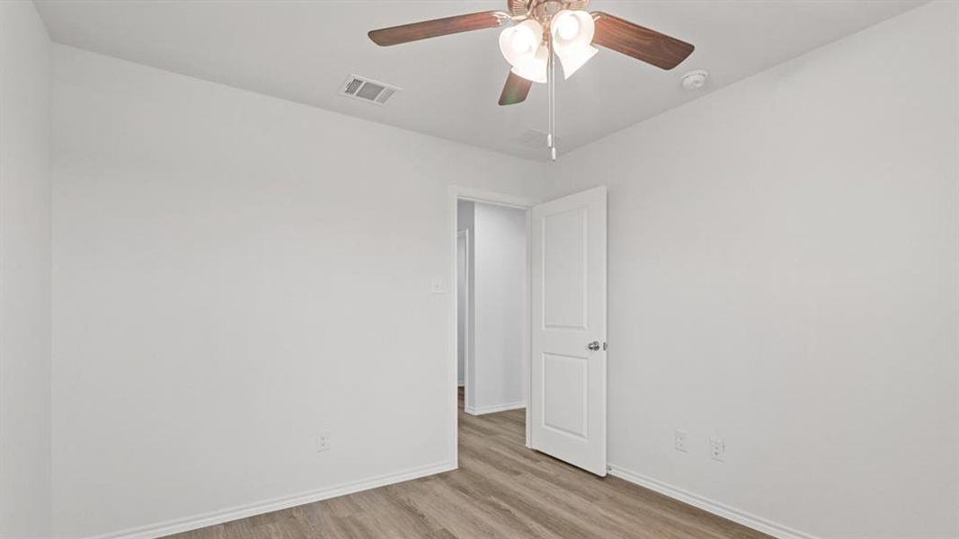 Room featuring wood-finish flooring, crisp white walls, white baseboards, and a ceiling fan with integrated lighting Room featuring wood-finish flooring, crisp white walls, white baseboards, and a ceiling fan with integrated lighting