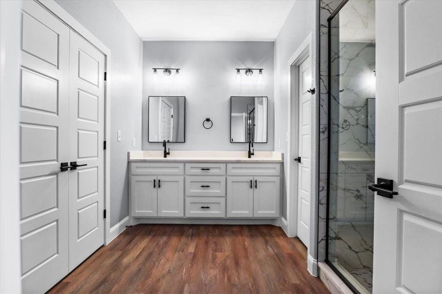 Bathroom featuring hardwood / wood-style floors, vanity, and a shower with shower door