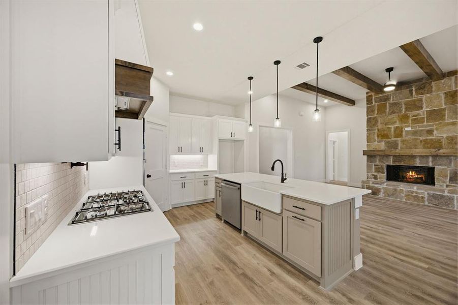 Gourmet kitchen featuring a gas cooktop, white subway tile backsplash, and an expansive island with a farmhouse sink