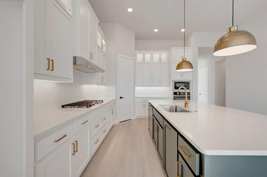 Two tone kitchen with two tone color scheme, a kitchen island with sink, glass insert cabinets, pendant lighting, and light wood-style floors Two tone kitchen with two tone color scheme, a kitchen island with sink, glass insert cabinets, pendant lighting, and light wood-style floors