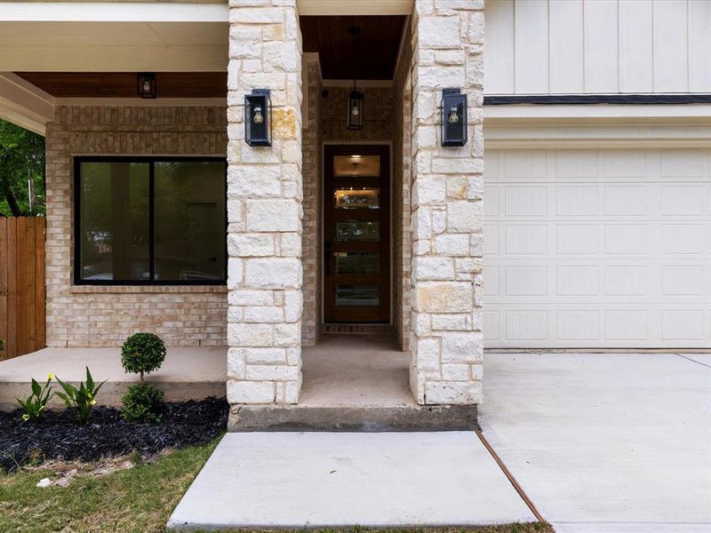 Property entrance with stone siding and a garage