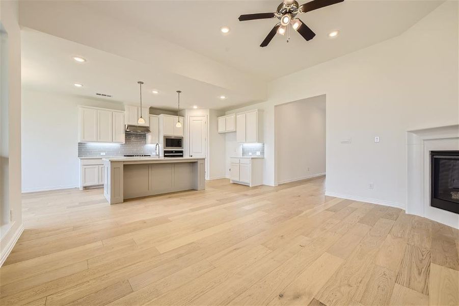 Kitchen with light hardwood / wood-style floors, a kitchen island with sink, ceiling fan, and stainless steel microwave