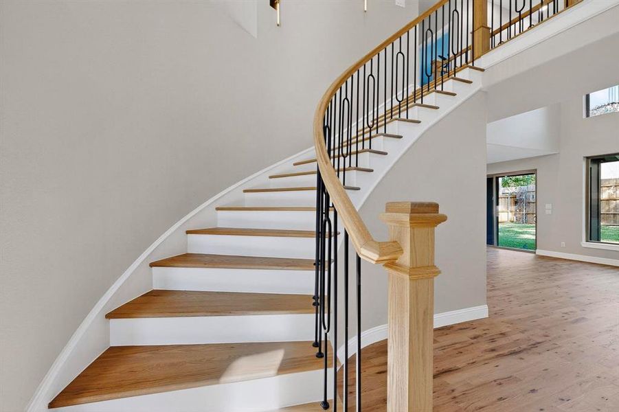 Stairway featuring wood finished floors and a towering ceiling