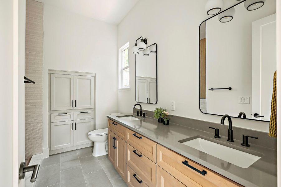 Full bathroom with toilet, tile patterned flooring, and double vanity