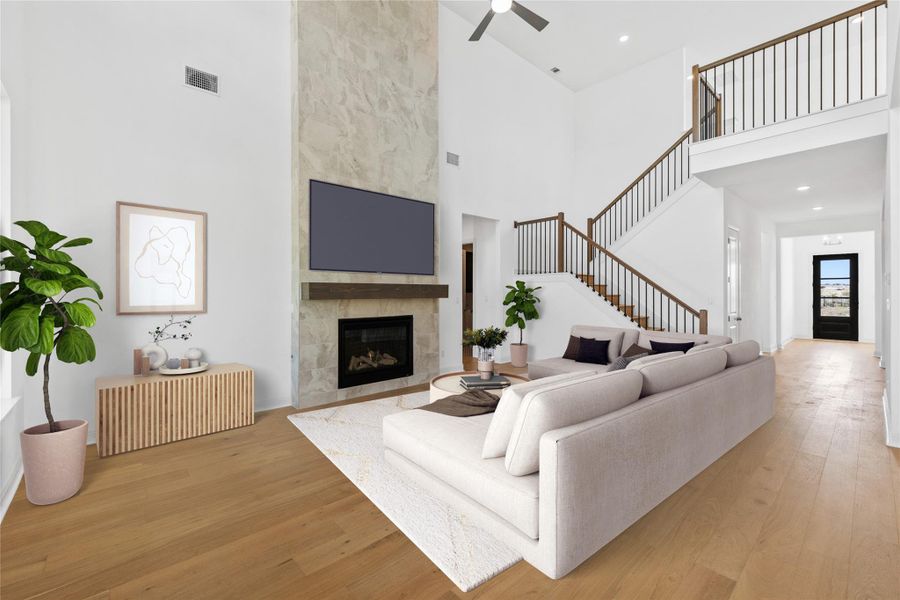 *Virtually Staged* Living area with a fireplace, light wood-type flooring, a ceiling fan, a high ceiling, and recessed lighting