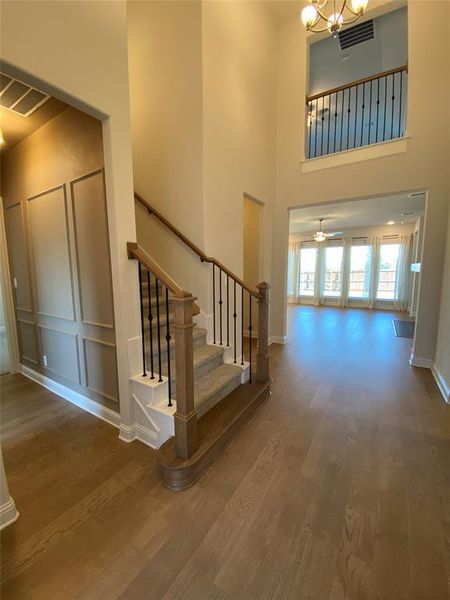 Stairs with wood finished floors, a high ceiling, ceiling fan, and a chandelier Stairs with wood finished floors, a high ceiling, ceiling fan, and a chandelier