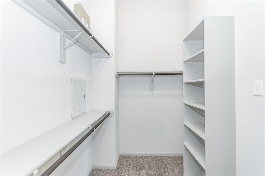 Organize in style with this spacious walk-in closet, complete with built-in shelves and multiple hanging options. Designed with functionality and storage in mind, this closet provides ample space to keep everything in order. A perfect complement to the luxurious primary suite.