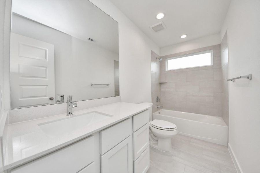 Secondary bath features tile flooring, bath/shower combo with tile surround, light stained wood cabinets, beautiful light countertop. Secondary bath features tile flooring, bath/shower combo with tile surround, light stained wood cabinets, beautiful light countertop.