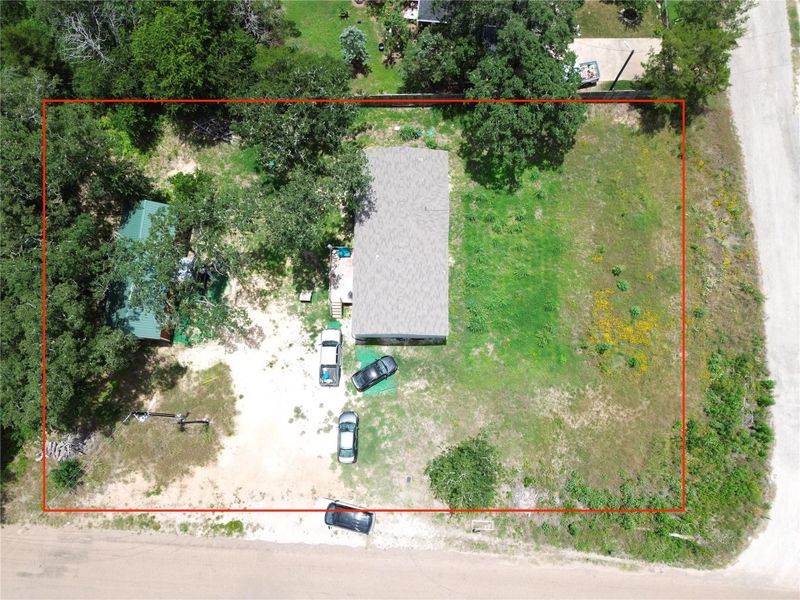 An aerial perspective showcases a generously sized, tree-dotted lot with two residential structures.