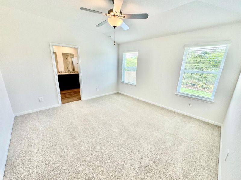 Unfurnished bedroom featuring carpet flooring, lofted ceiling, ensuite bathroom, and ceiling fan Unfurnished bedroom featuring carpet flooring, lofted ceiling, ensuite bathroom, and ceiling fan